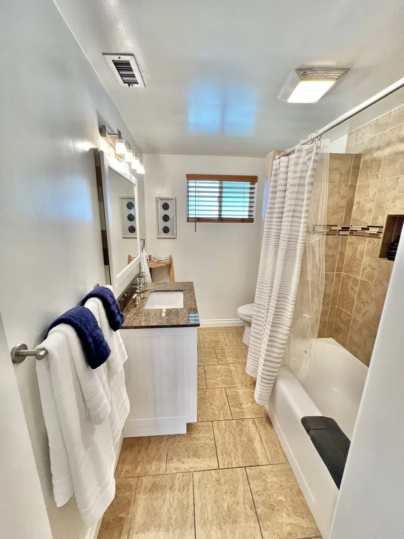 Bathroom with a tiled tub-and-shower combination, vanity, mirror and folded towels