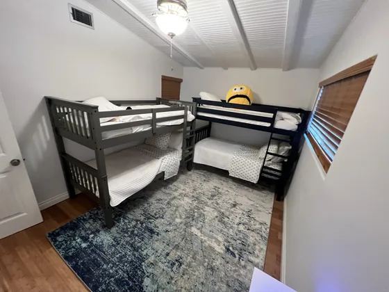 Kids' bunk room with two wooden twin-over-twin bunk beds on a patterned rug
