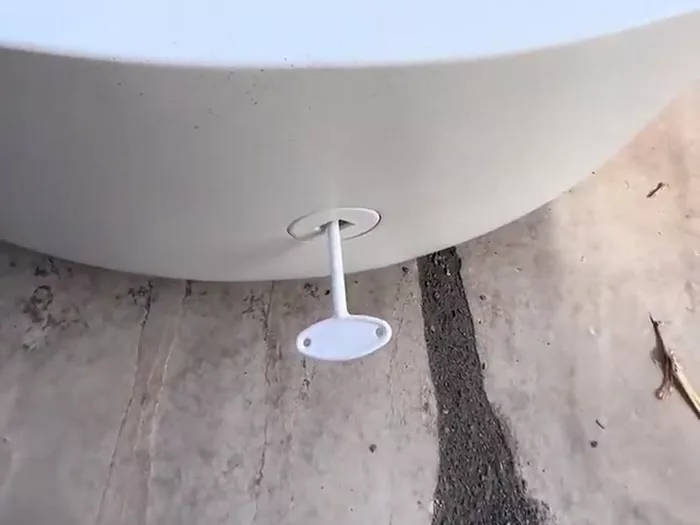 The white control key inserted into the valve at the base of the round white fire pit, used to set the flame height