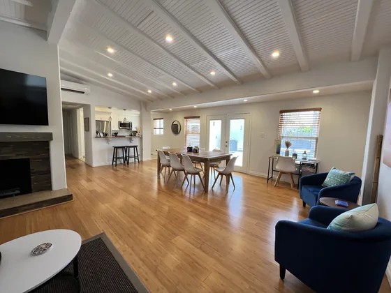 The open great room with vaulted white plank ceiling, gas fireplace and hardwood floors