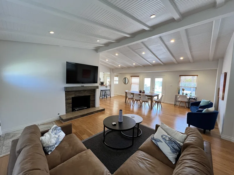 Great room seating area with two sofas, a round coffee table and a TV above the gas fireplace