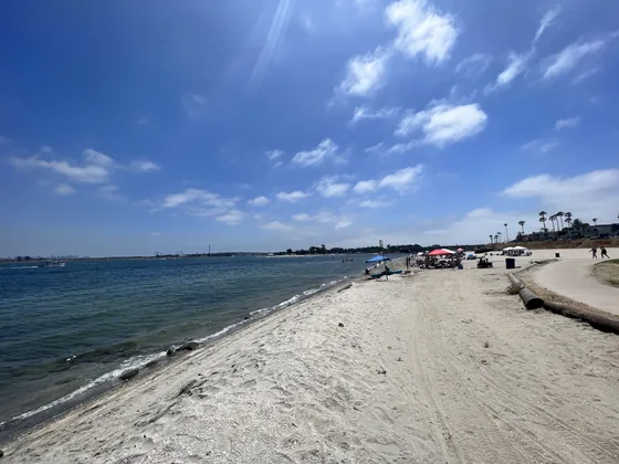 Wide sandy beach on Mission Bay under a blue sky with scattered cloud