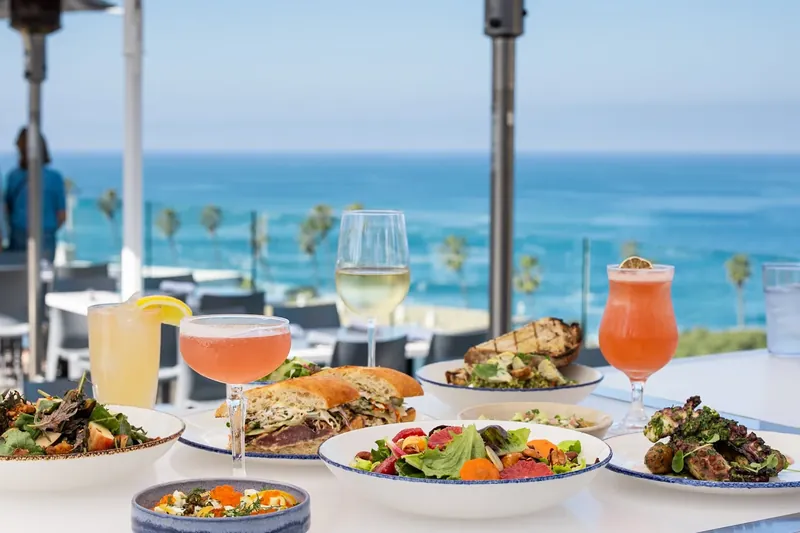 Plates and drinks on the ocean terrace at George’s at the Cove, the Pacific behind