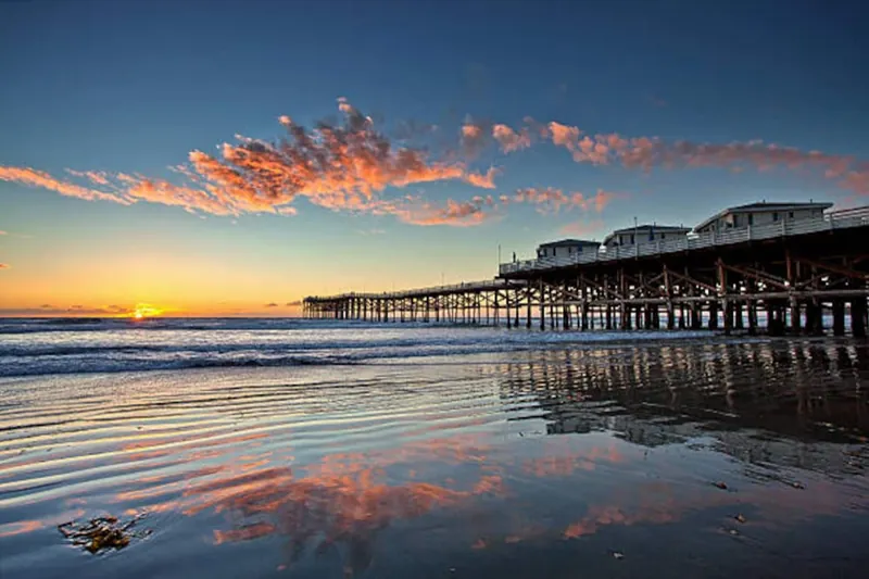 Crystal Pier at sunset with the colours of the sky reflected in the wet sand